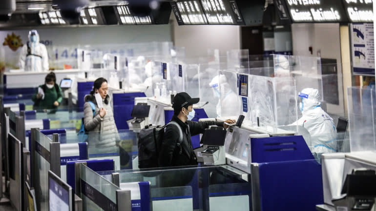 Các quan chức xuất nhập cảnh trong trang phục bảo hộ giúp hành khách làm thủ tục hải quan vào tháng trước tại sân bay quốc tế Qingdao Liuting ở Qingdao, Trung Quốc. © Hình ảnh Getty