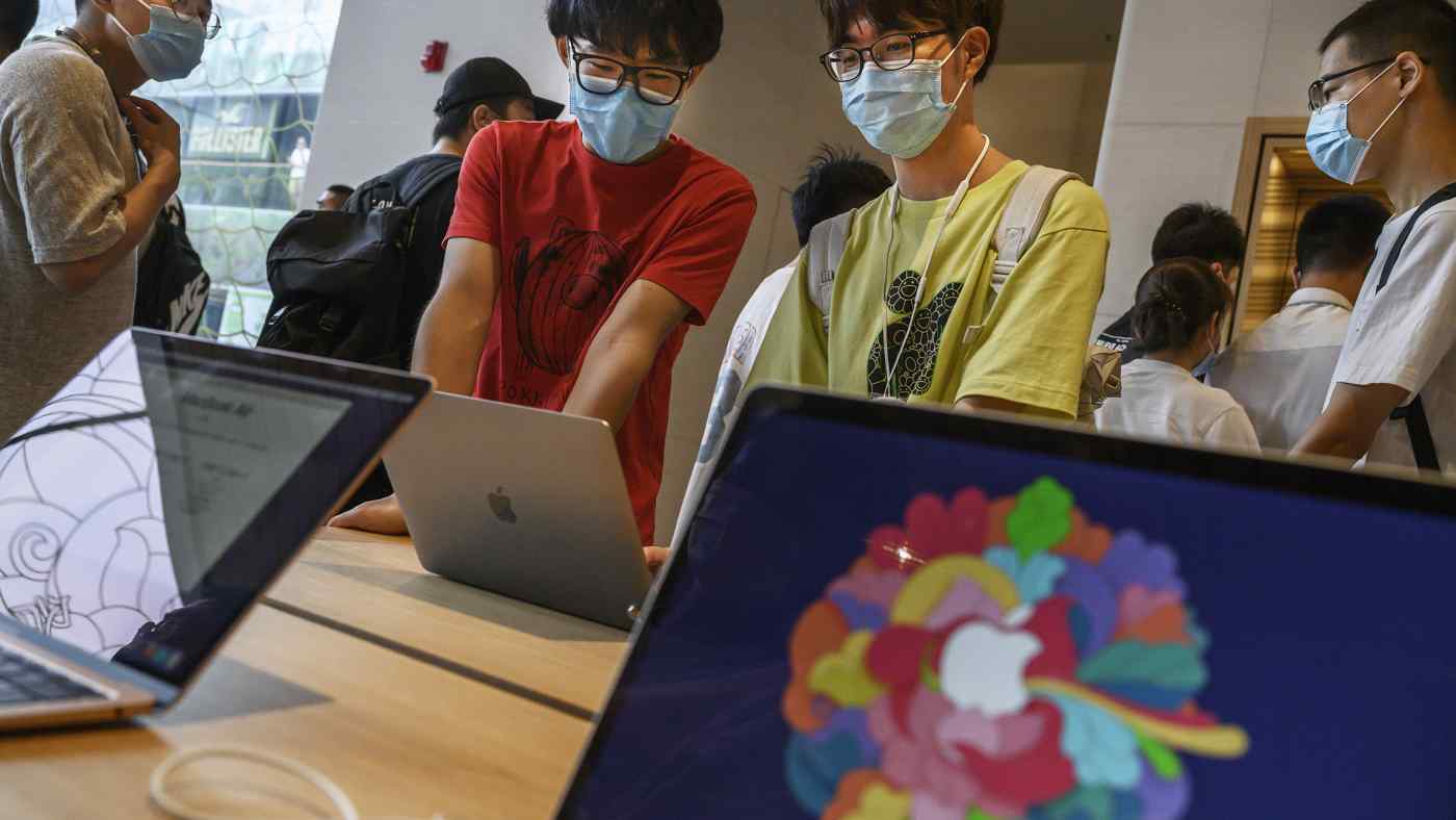 Mọi người xem sản phẩm tại một cửa hàng Apple Store ở Bắc Kinh: Tình trạng thiếu chất bán dẫn ngày càng trầm trọng đang bắt đầu ảnh hưởng đến hoạt động sản xuất, bất chấp việc nhà sản xuất thiết bị gia dụng của Mỹ mua nhiều. © Hình ảnh Getty