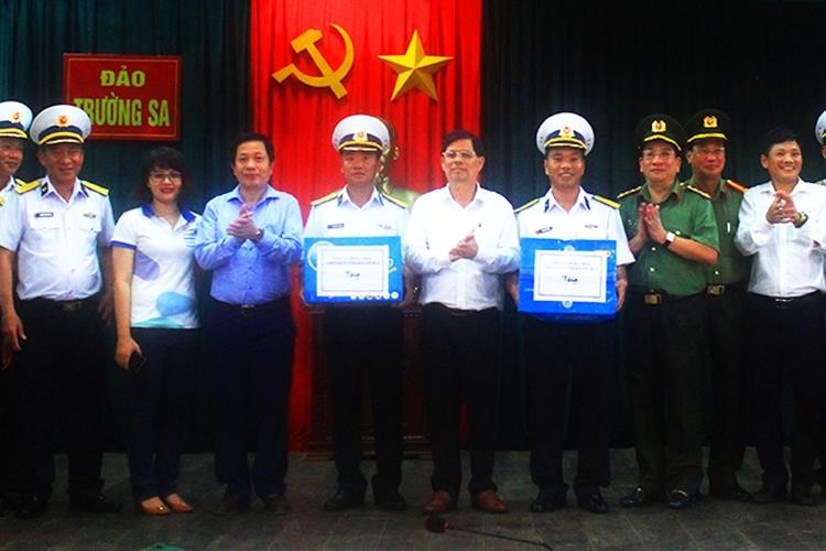 Ông Nguyễn Tấn Tuân (giữa) và ông Hà Quốc Trị (thứ tư từ bên trái sang) cùng đoàn công tác trao quà cho quân và dân thị trấn Trường Sa.