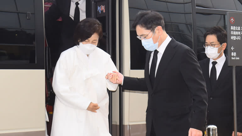 Mặc đồ tang trắng, góa phụ Hong Ra-hee, trái, được con trai Lee Jae-yong giúp đỡ tại Trung tâm Y tế Samsung ở Seoul vào ngày 28 tháng 10 năm 2020. © Yonhap / EPA / Jiji