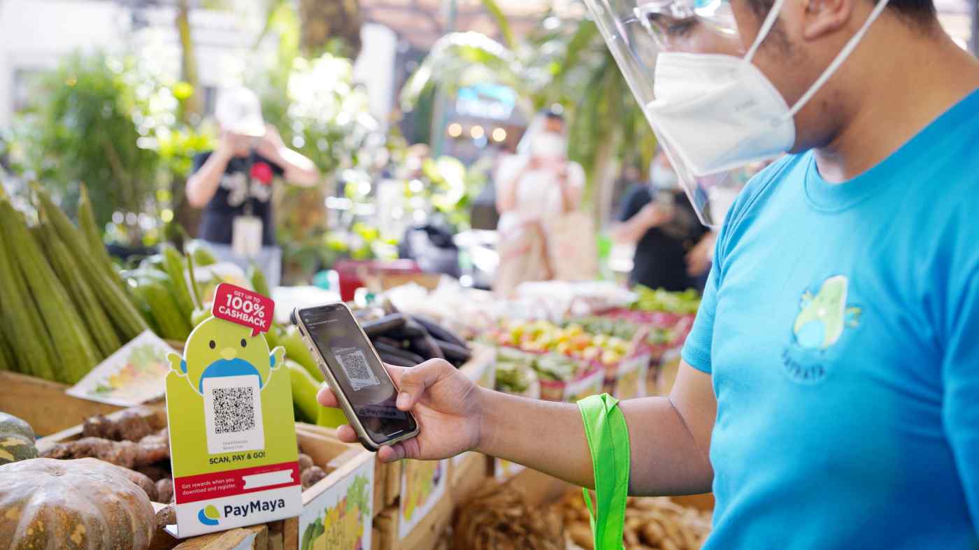 Một người mua sắm sử dụng ví di động PayMaya của Voyager để mua hàng tại một khu chợ ngoài trời ở Philippines. (Ảnh: Voyager Innovations)
