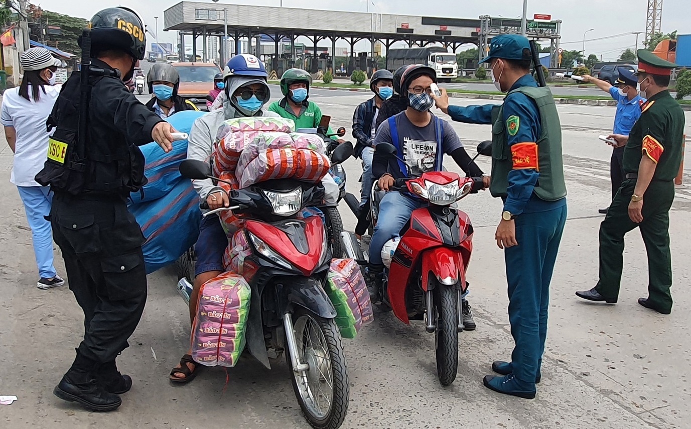 Người dân đo thân nhiệt và khai báo y tế tại chốt kiểm dịch ở chân cầu Đồng Nai