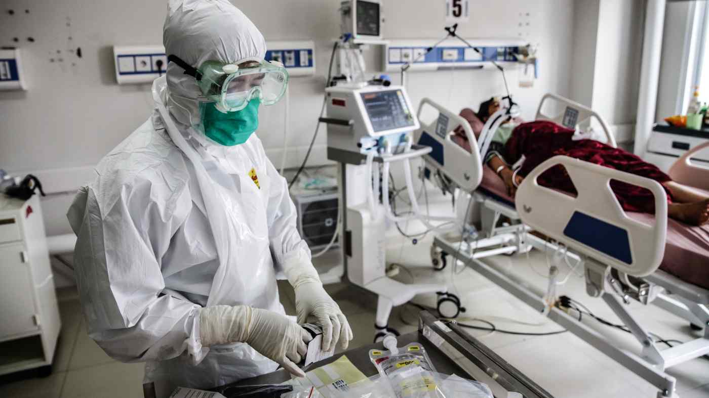 Một nhân viên của đơn vị chăm sóc đặc biệt tiến hành kiểm tra y tế cho một bệnh nhân COVID-19 tại Bệnh viện Thành phố Bogor, Indonesia vào ngày 23 tháng 6. © EPA / Jiji