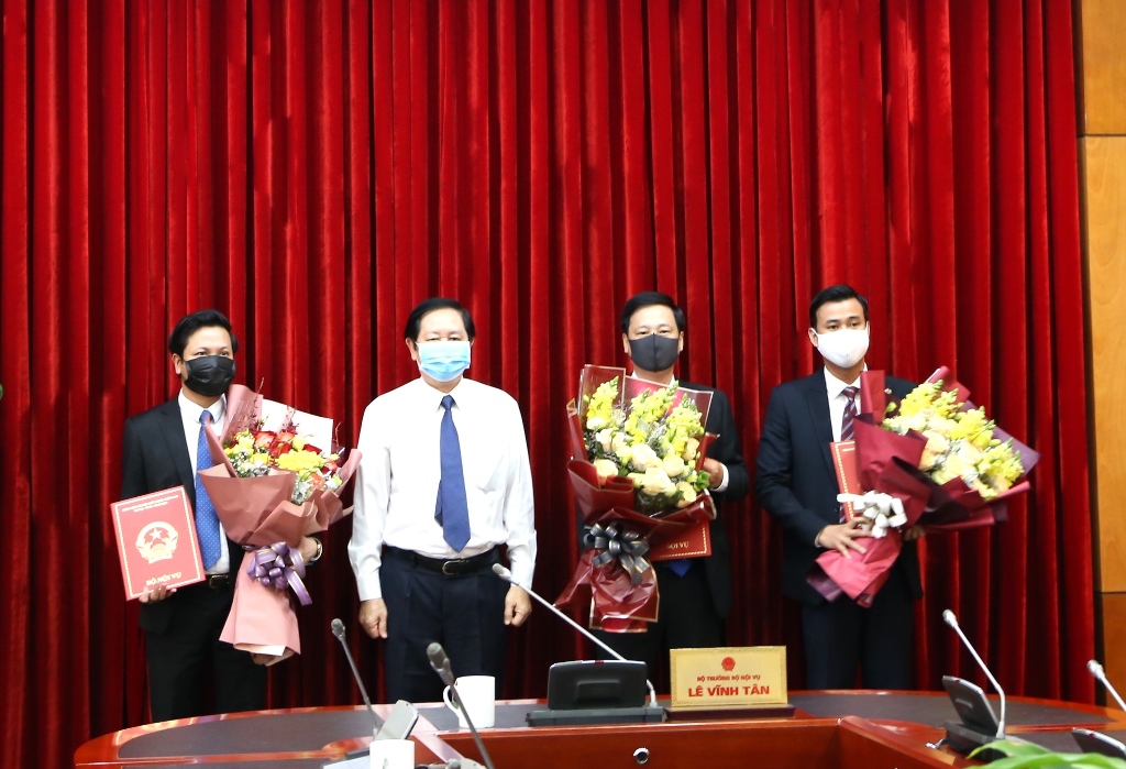 Bộ trưởng Bộ Nội vụ Lê Vĩnh Tân (áo trắng) trao quyết định và tặng hoa chúc mừng đồng chí Nguyễn Phi Đa (bìa phải) và 2 đồng chí khác công tác tại Bộ Nội vụ vào ngày 26/03/2020