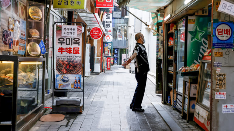 Một người bán hàng dang tay trên con đường vắng khách ở Seoul vào ngày 9 tháng 7. © Reuters