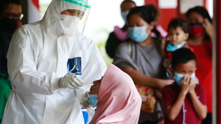 Một nhân viên y tế trong trang bị bảo hộ cá nhân lấy mẫu tăm bông từ một phụ nữ để kiểm tra COVID-19 trong quá trình kiểm tra hàng loạt tại một trường học ở Jakarta vào ngày 2 tháng 7. © Reuters