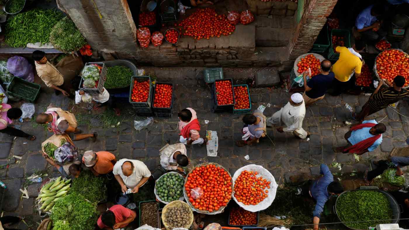 Mọi người mua sắm tại một chợ rau bán buôn đông đúc sau khi nhà chức trách nới lỏng các hạn chế về coronavirus, sau khi số trường hợp COVID-19 giảm, ở các khu phố cổ của Delhi, Ấn Độ, ngày 23 tháng 6. © Reuters
