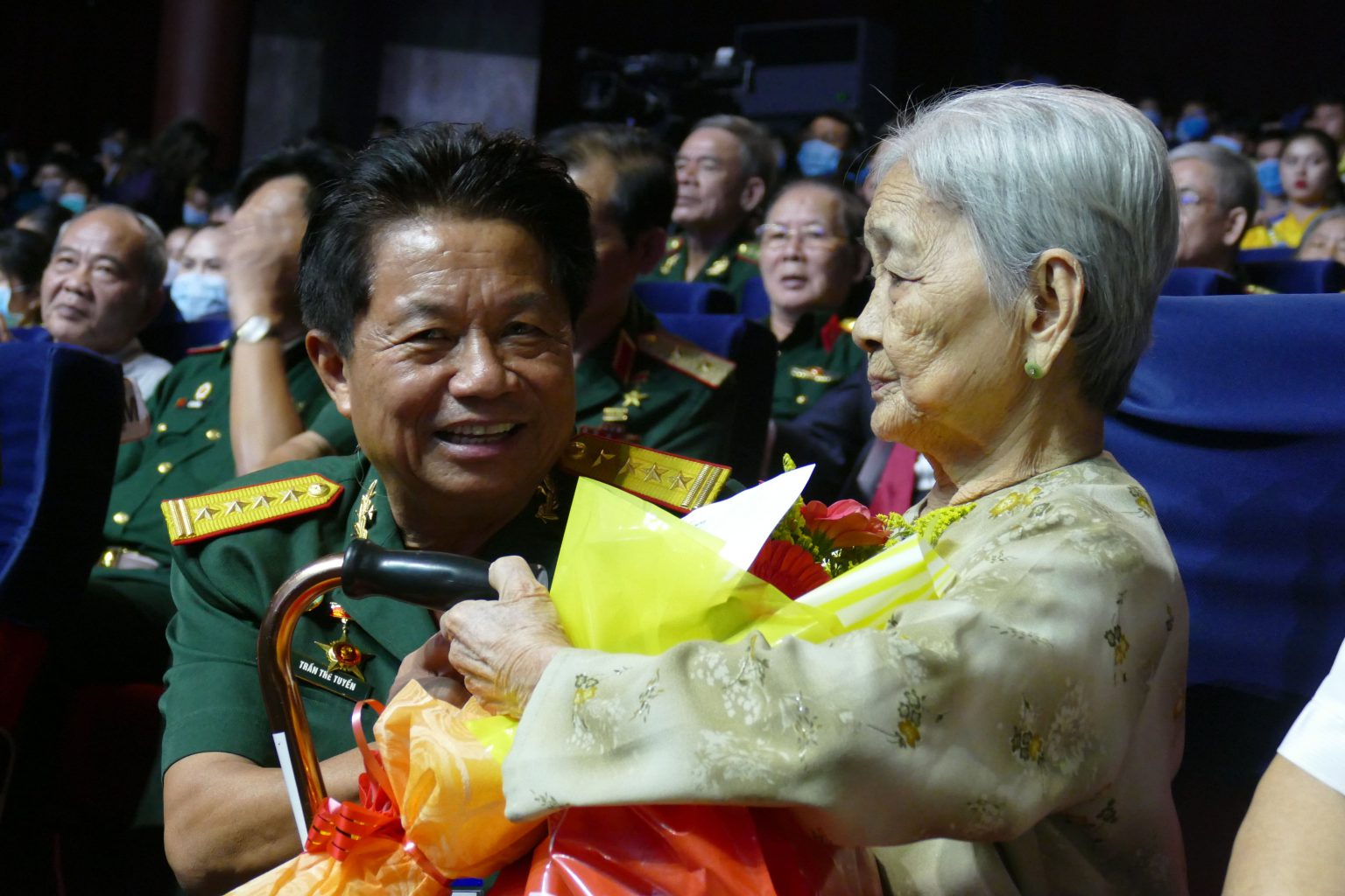 Đại tá Trần Thế Tuyển - Chủ tịch Hội hỗ trợ Gia đình Liệt sỹ TP.HCM, tặng hoa cảm ơn các Mẹ VN Anh hùng trong Chương trình nghệ thuật đặc biệt 
