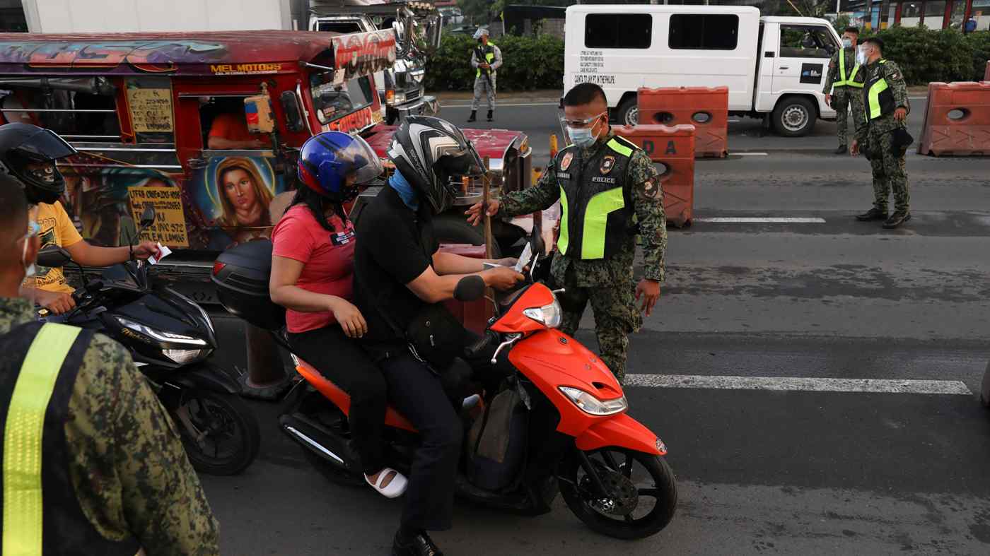 Các nhân viên cảnh sát kiểm tra người lái xe ô tô tại một trạm kiểm soát trong một cuộc chốt chặn nghiêm ngặt hơn ở ngoại ô thành phố Marikina, Philippines, vào ngày 6 tháng 8. © AP
