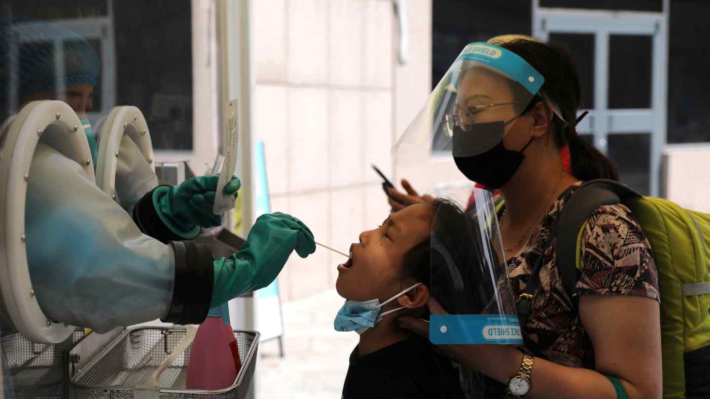 Một nhân viên y tế thu thập một miếng gạc từ một cô gái tại một địa điểm xét nghiệm axit nucleic di động bên ngoài một nhà ga ở Bắc Kinh vào ngày 6 tháng 8. © Reuters