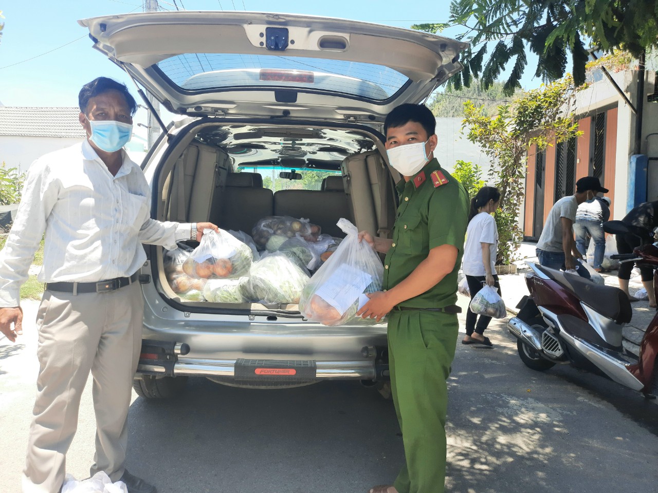 Trung uy Phan Khánh công an xã Hòa Sơn, huyện Hòa Vang và ông Phạm Thanh Sinh - trưởng thôn Đại La, đang phụ bê thực phẩm rau củ...đi chợ về cho người dân.