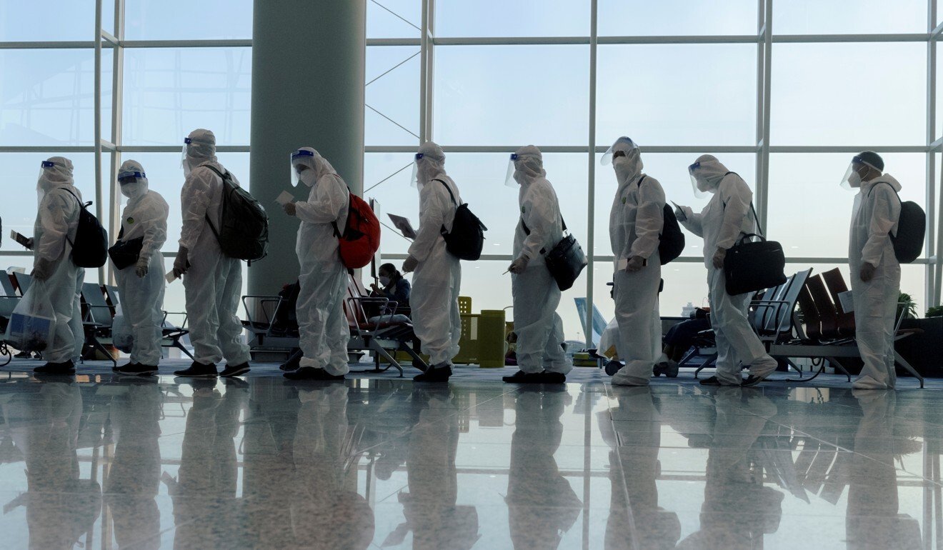 Các hành khách trong trang phục bảo hộ lên chuyến bay quốc tế ở sân bay Hồng Kông
