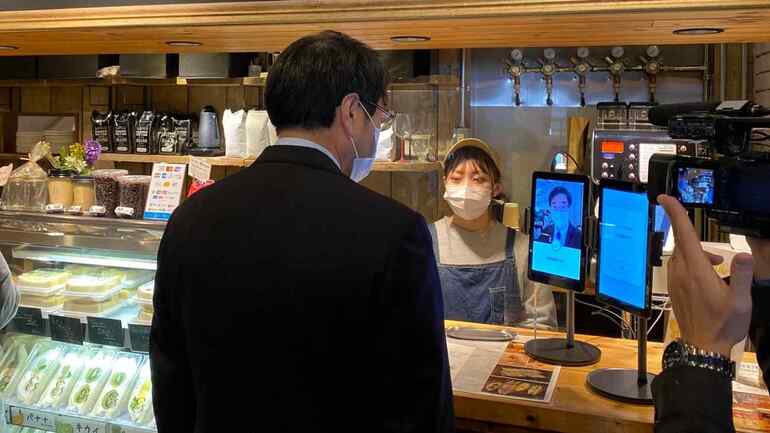 Thị trưởng Niigata Yaichi Nakahara dùng thử hệ thống nhận dạng khuôn mặt của Glory tại một quán cà phê