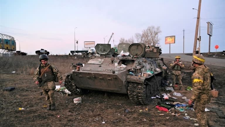 Các binh sĩ Ukraine kiểm tra một chiếc xe bọc thép bị phá hủy, mà họ cho là thuộc về quân đội Nga, bên ngoài Kharkiv. © Reuters