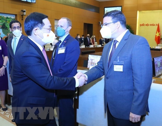 Top legislator, NA Chairman Vuong Dinh Hue (L) greets participants in the meeting in Ha Noi on March 9