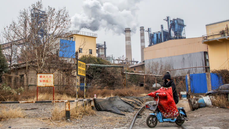 Một phụ nữ đi xe tay ga ngang qua một nhà máy thép ở tỉnh Hà Nam, Trung Quốc. Bắc Kinh đã và đang hạn chế sản xuất thép để đáp ứng các mục tiêu giảm phát thải. © Reuters