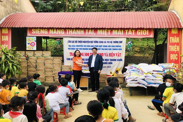 Thầy Đặng Xuân Viên, hiệu trưởng trường tiểu học Thanh Xuân thay mặt nhà trường nhận 300 triệu đồng và các suất quà từ bà Nguyễn Thị Vân Anh, đại diện CLB