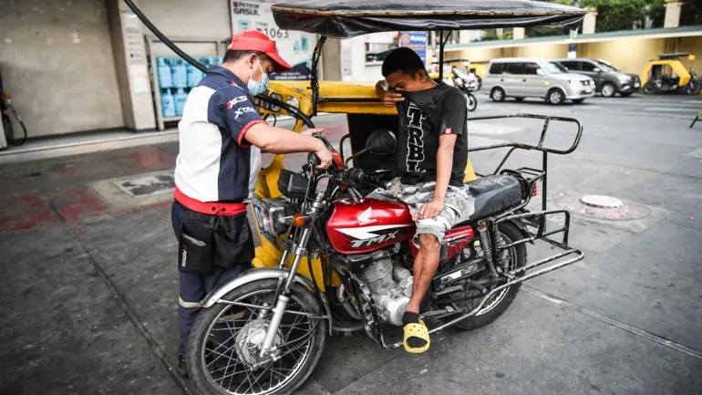 Một người phục vụ đổ xăng cho xe ba bánh tại một trạm xăng ở Manila vào ngày 8 tháng 3. Philippines đã phát hành 3 tỷ peso (57 triệu đô la) trợ cấp nhiên liệu cho người lái xe công ích và nông dân vào đầu tháng này. © AFP / Jiji