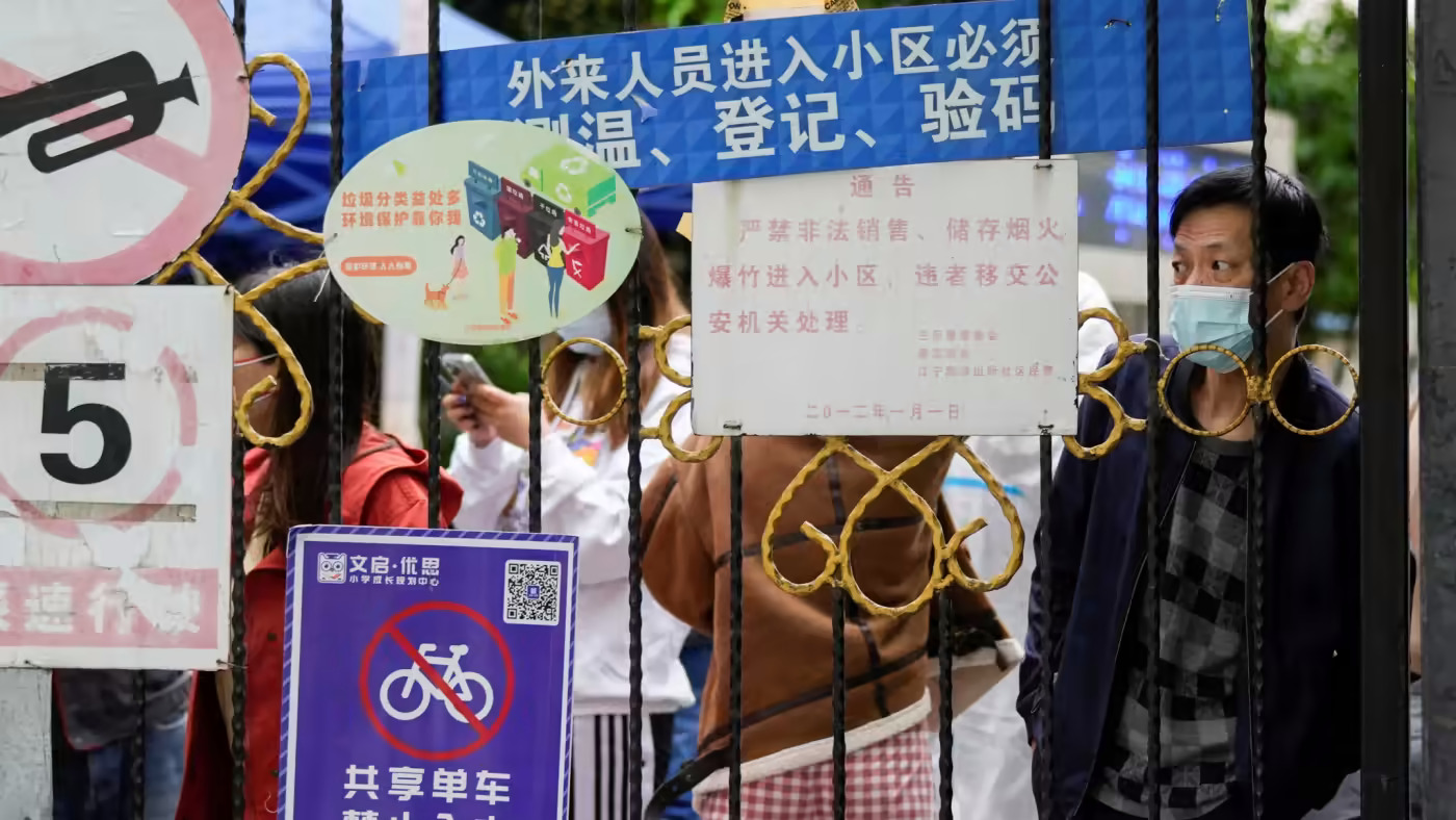 Người dân chờ giao đồ ăn sau cổng một khu dân cư ở Thượng Hải. Việc đóng cửa thành phố đã gây ra một thiệt hại nghiêm trọng cho chi tiêu của người tiêu dùng. © Reuters