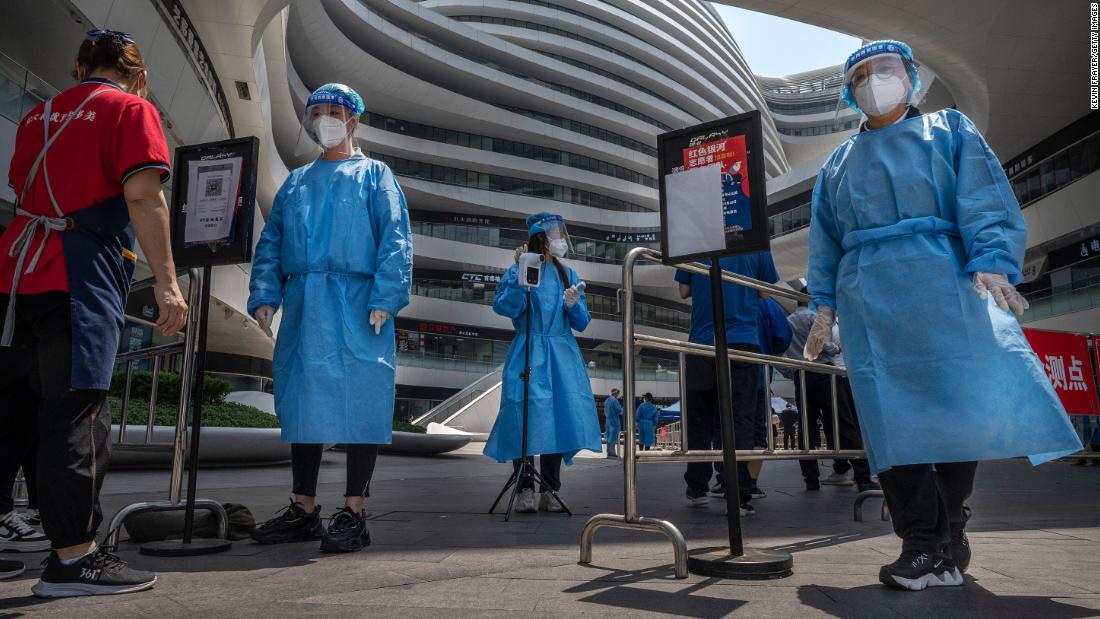 Nhân viên y tế mặc quần áo bảo hộ tại lối vào khu thử nghiệm Covid-19 tại một khu phức hợp mua sắm ở Bắc Kinh.
