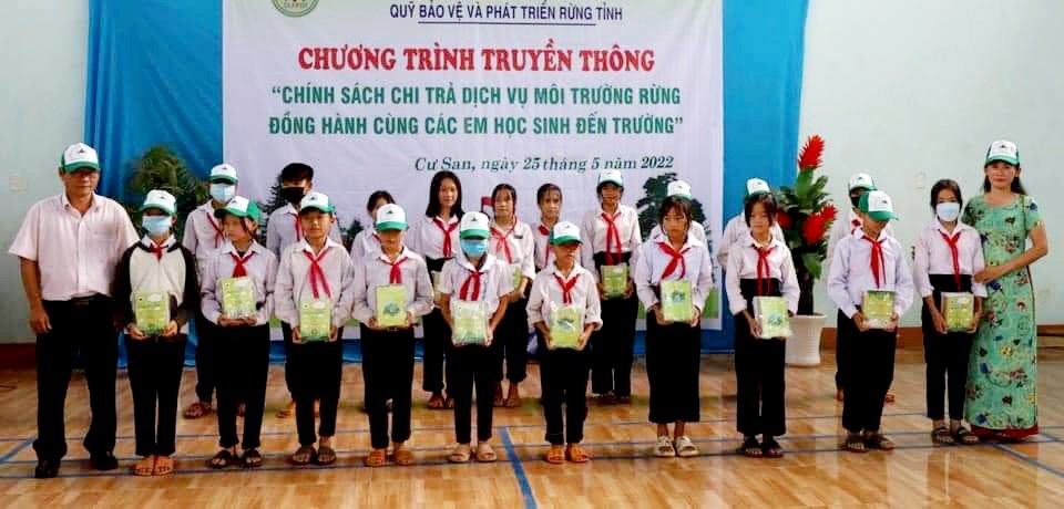 Ông Nguyễn Minh Quân - Phó giám đốc Quỹ Bảo vệ và Phát triển rừng tỉnh Đắk Lắk và lãnh đạo Trường Phổ thông Dân tộc bán trú Trung học cơ sở Tô Hiệu trao tặng vở viết cho các em học sinh.