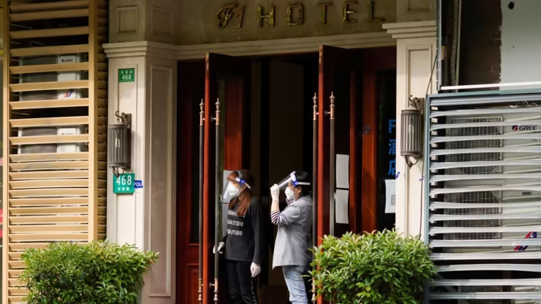 Phụ nữ ở lối vào của một khách sạn ở Thượng Hải. Những hạn chế tại các thành phố lớn nhất và giàu nhất Trung Quốc đã kìm hãm hoạt động du lịch trong nước. © Reuters