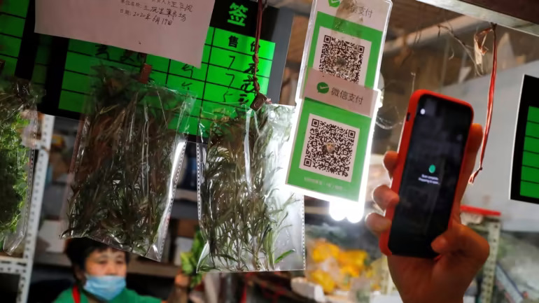 Một người mua sắm sử dụng dịch vụ thanh toán kỹ thuật số WeChat Pay tại một khu chợ mới ở Bắc Kinh: Ở Trung Quốc, các ứng dụng thanh toán đã là cách chính mà 90% người dân thành thị thanh toán cho các giao dịch mua hàng ngày. © Reuters