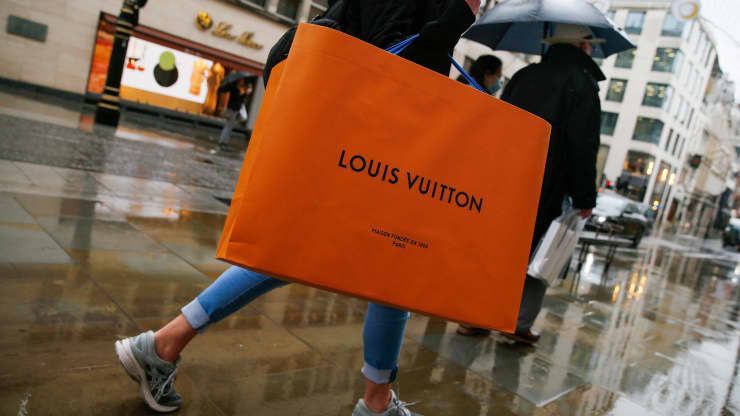 Một người đi bộ mang theo một chiếc túi mua sắm Louis Vuitton, từ một cửa hàng do LVMH Moet Hennessy Louis Vuitton SE điều hành, trên Phố New Bond ở London, Vương quốc Anh, vào thứ Tư, ngày 21 tháng 10 năm 2020.