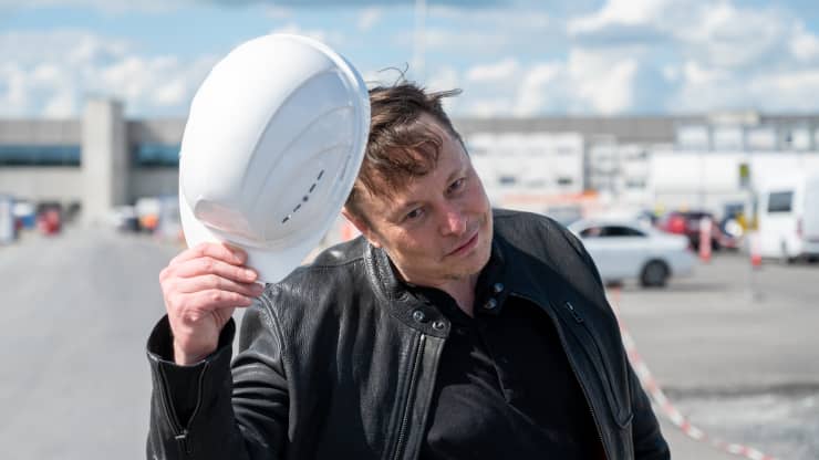 Ngày 17 tháng 5 năm 2021, Brandenburg, Grünheide: Elon Musk, Giám đốc điều hành Tesla, đứng trên công trường xây dựng nhà máy Tesla và chào với chiếc mũ cứng của mình.