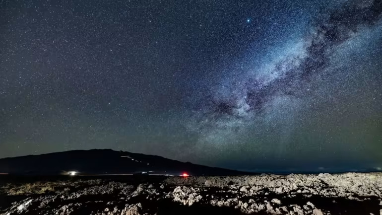 Một bầu trời đầy sao trên Mauna Kea, với ánh đèn pha của những chiếc xe du lịch đang đổ xuống chiếu trên sườn núi. (Ảnh của Akira Takemura)
