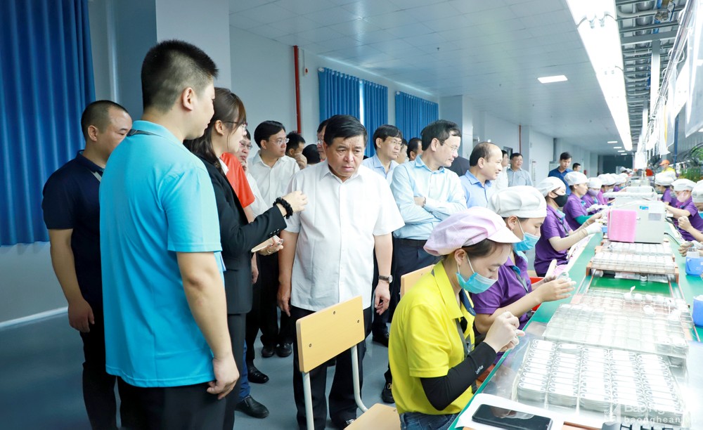 Bộ trưởng Nguyễn Chí Dũng nghe giới thiệu về dây chuyền sản xuất tại nhà máy của Công ty LuxShare ICT đầu tư tại VSIP Nghệ An. Ảnh: Thành Duy