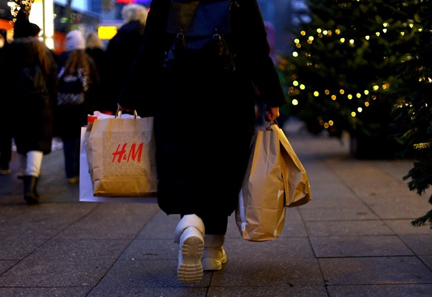 Một người phụ nữ mang theo chiếc túi mua sắm có nhãn hiệu của chuỗi cửa hàng thời trang H&M khi đi dọc phố mua sắm Kurfuerstendamm vào cuối tuần thứ hai của mùa du lịch tháng 12/2022 ở Berlin, Đức. Ảnh: REUTERS/Lisi Niesner/File Photo