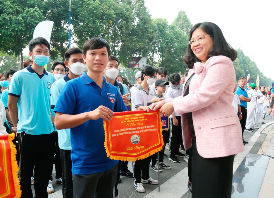Bà Nguyễn Trường Nhật Phượng, Phó Chủ tịch Hội đồng nhân dân tỉnh Bình Dương trao cờ lưu niệm cho các đơn vị về tham dự chương trình