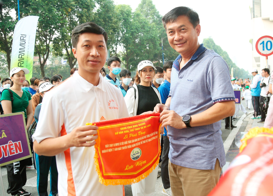 Mr. Nguyen Van Loc, Member of the Standing Committee of the Provincial Party Committee - Head of the Provincial Party Committee's Mass Mobilization Department, and Chairman of the Vietnam Fatherland Front Committee of Binh Duong Province presented souvenir flags to units attending the program.