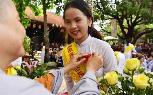 Một nữ sinh được sư thầy chùa Văn Trì (Hà Nội) cài hoa hồng đỏ lên áo trong dịp lễ Vu Lan. Ảnh: Giang Huy.