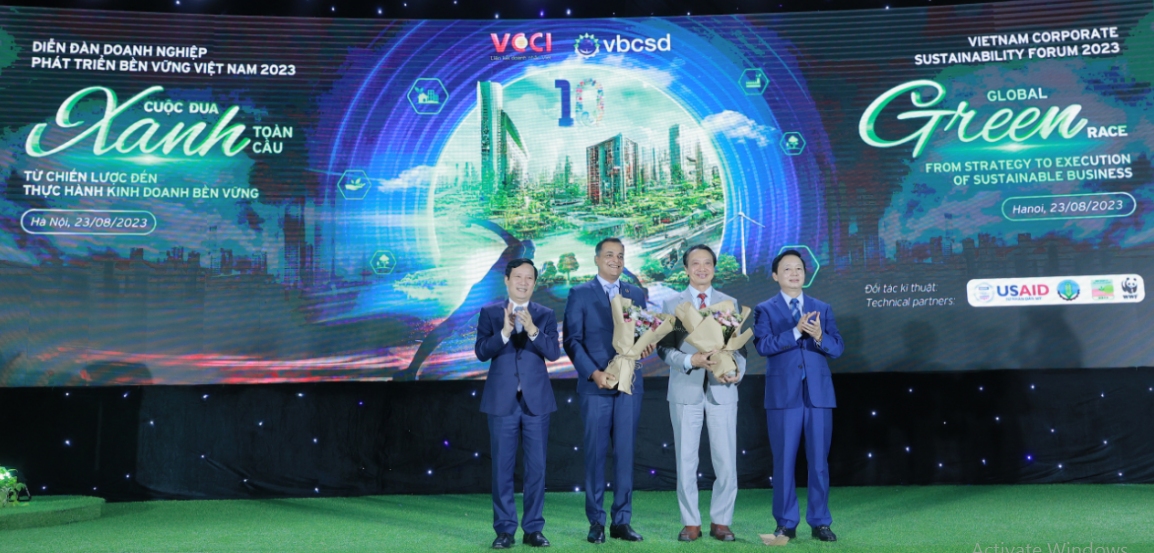 Phó Thủ tướng Trần Hồng Hà (phải, ngoài cùng) trao tặng hoa cho Chủ tịch VBCSD Nguyễn Quang Vinh (thứ 2, từ phải sang) và đồng Chủ tịch VBCSD Binu Jacob (thứ 3, từ phải sang) để ghi nhận chặng đường