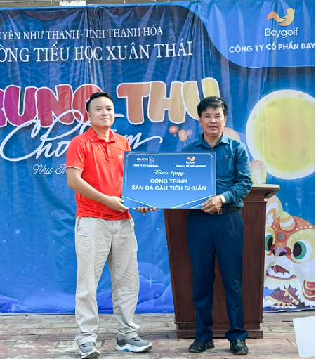 Đại diện Công ty Baygolf lên trao chứng nhận xây dựng một sân đá cầu tiêu chuẩn trị giá 25.000.000 đ cho ông Nguyễn Như Hùng - Hiệu trưởng nhà trường.