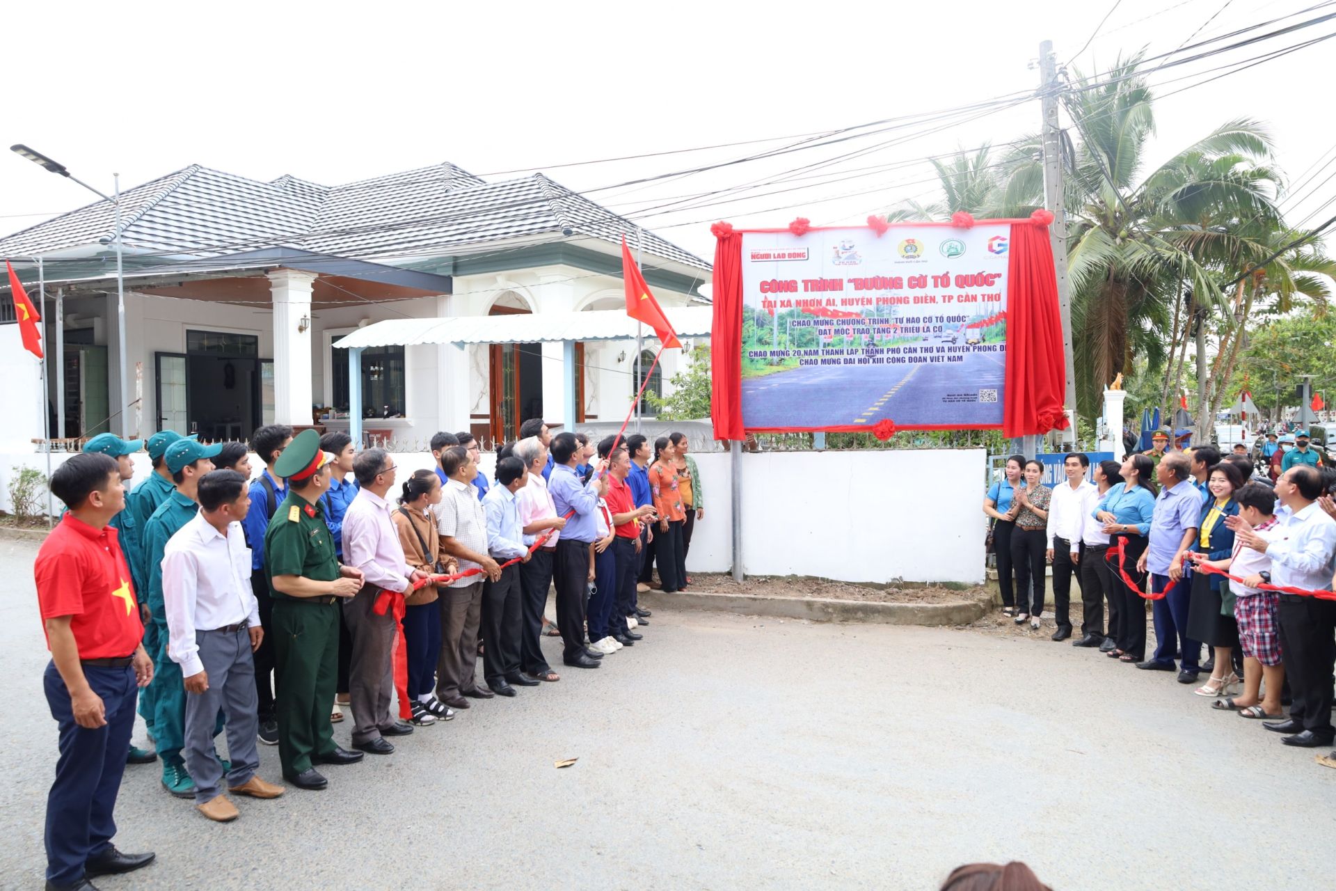 Các đại biểu và nhân dân thực hiện nghi thức khánh thành công trình “Đường cờ Tổ quốc” tại huyện Phong Điền.