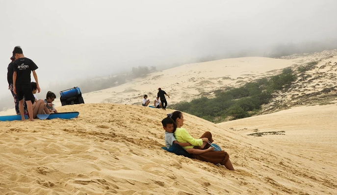 Nhiều du khách đến Quảng Bình say mê trò trượt cát trên bãi cát phẳng lỳ