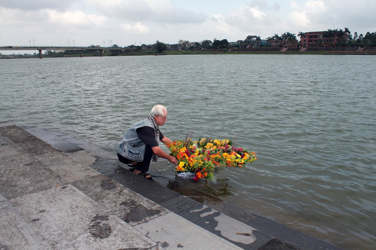 Nhà báo Lê Bá Dương thả hoa viếng đồng đội bên bờ sông Thạch Hãn