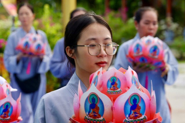 Buddhists reverently offering lotus flowers at the Medicine Buddha prayer